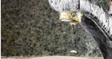 A water faucet covered in mineral deposits from hard water