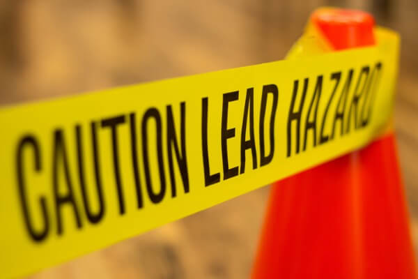 An image of yellow tape that says “Caution Lead Hazard” to show the health risks of lead poisoning. 