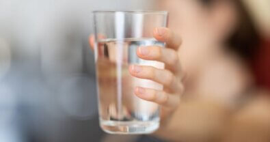A woman holds a glass of clean water up to the camera