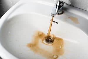 billede af snavset brunt vand, der løber ind i en hvid vask. Ser meget usundt ud og har brug for klorinjektionssystem
