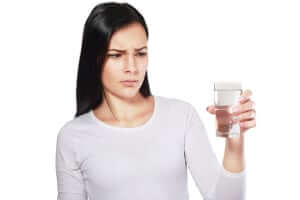 Image of woman holding glass of water making a face like the water smells and needs water treatment