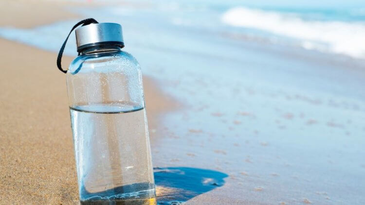 A reusable water bottle on a beach