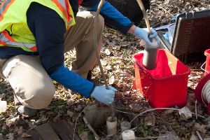 Photo of a worker siphoning groundwater with a kit for testing water quality.