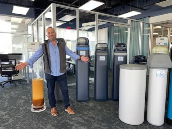 Drew Wilson standing in front of salt-based water softeners at Angel Water