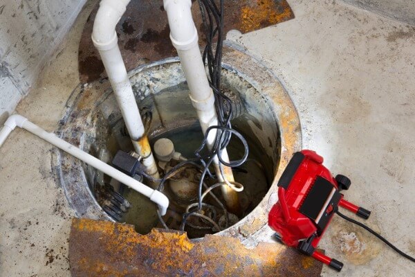 Image of a sump pump being repaired in a basement.