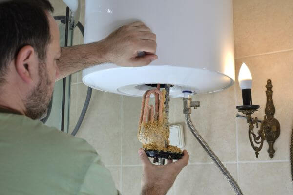 Worker inspecting calcium buildup in a water heater