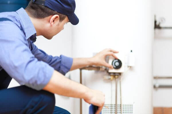 Image of a licensed plumber inspecting a water heater