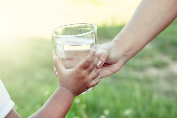 Image of a woman handing a glass of water to her child
