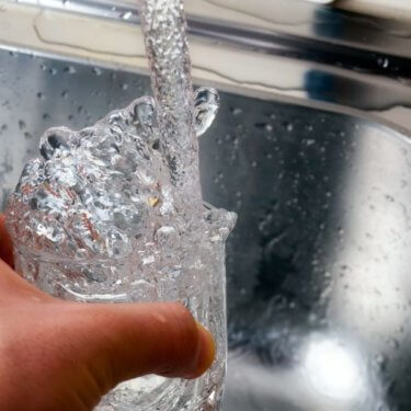 Person getting a glass of clean water from a sink