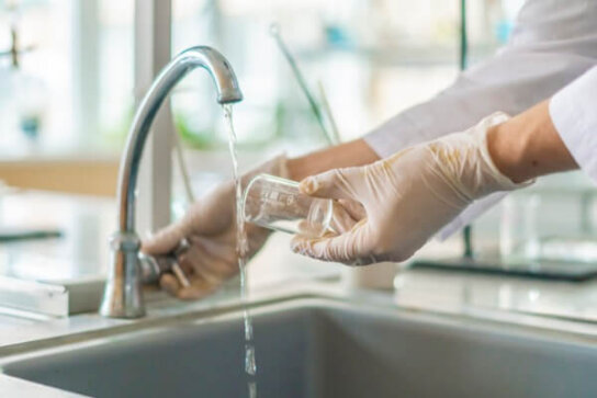 Image of a person collecting tap water for water testing