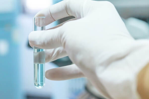 Image of a gloved hand holding a test tube full of water