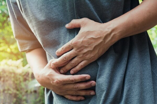 A man experiencing stomach issues from water holds his stomach in pain