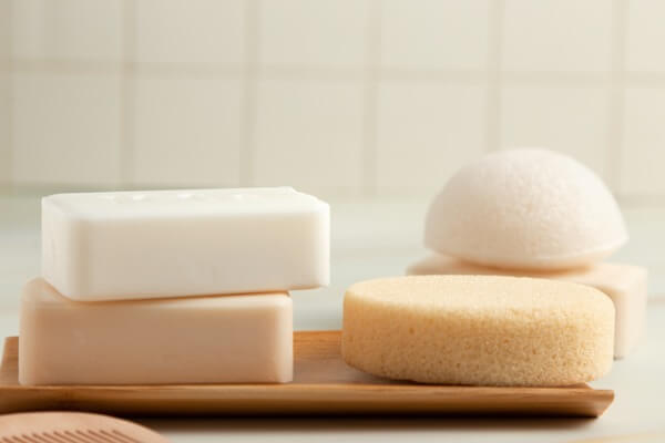 Two bars of soap and two sponges against a neutral background