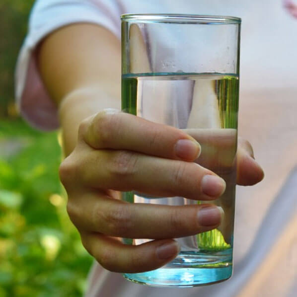 Image of a man pouring tap water into a glass.