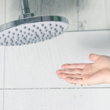 Hand touching softened water from a showerhead