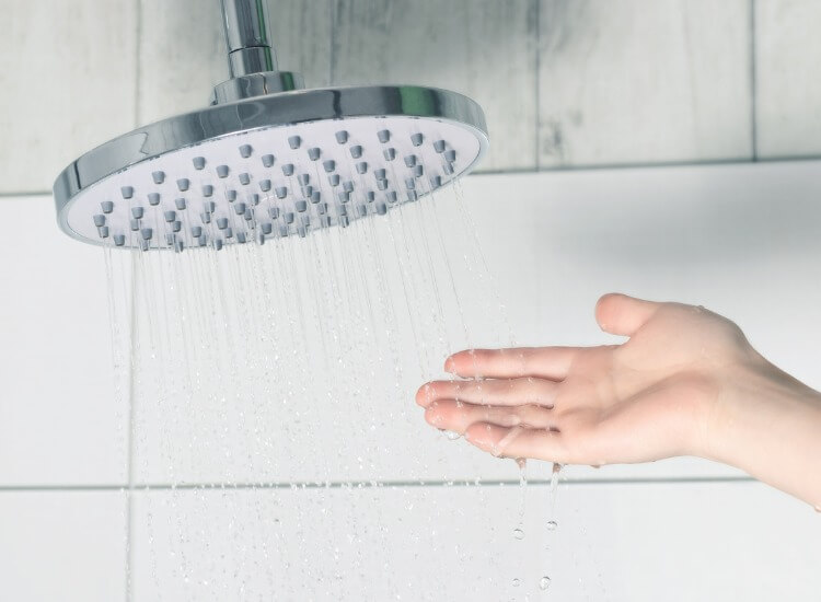 Hand touching softened water from a showerhead
