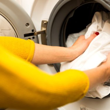 A woman finding rust stains on clothes in her washing machine.
