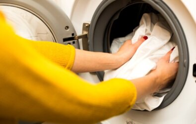 A woman finding rust stains on clothes in her washing machine.
