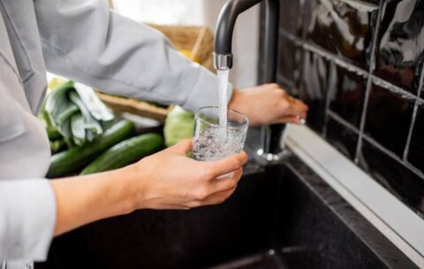 A man pouring himself a glass of water from the sink