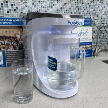 Countertop reverse osmosis system next to a glass of pure water