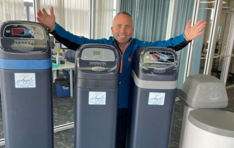 Andrew Wilson of Angel Water standing by water softeners