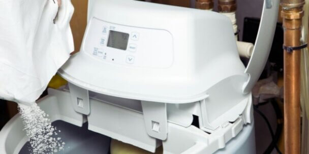 Close-up of someone pouring salt into a water softener system