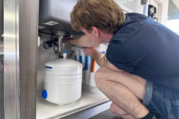 Someone installing an under sink ro system for the best reverse osmosis systems 2025